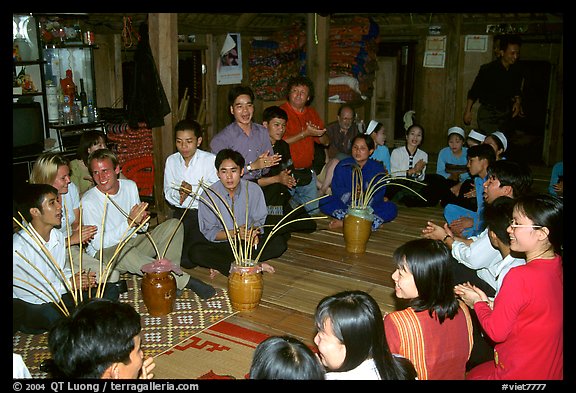 Guests in a thai house gather around jars of rau can alcohol, Ban Lac, Mai Chau. Northwest Vietnam