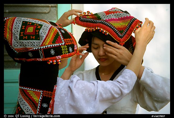 A thai woman helps her friend with her elaborate headdress, Son La. Northwest Vietnam