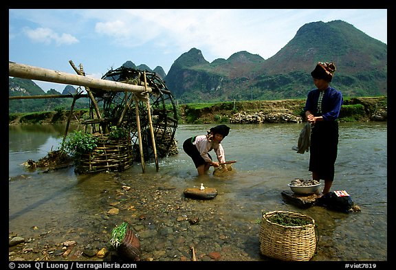 Thai women washing laundry and collecting water plants near an irrigation wheel, near Son La. Northwest Vietnam