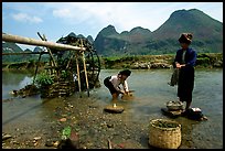 Thai women washing laundry and collecting water plants near an irrigation wheel, near Son La. Northwest Vietnam ( color)