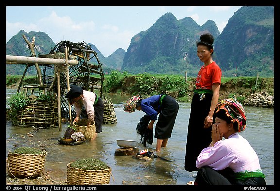 Thai women washing laundry and collecting water plants near an irrigation wheel, near Son La. Northwest Vietnam