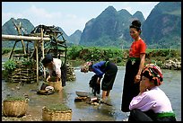 Thai women washing laundry and collecting water plants near an irrigation wheel, near Son La. Northwest Vietnam