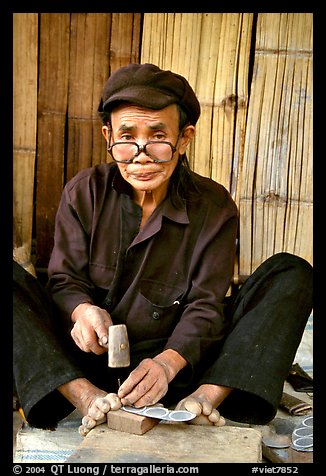 Black Dzao man making the decorative coins used in the children hats, between Tam Duong and Sapa. Northwest Vietnam