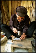 Dzao man crafting the decorative coins used in the children hats, between Tam Duong and Sapa. Northwest Vietnam (color)