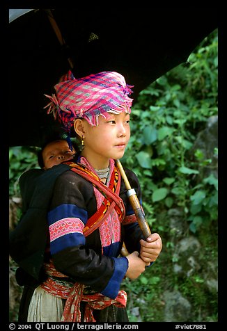 Hmong girl sheltering herself and her younger sibling with an unbrella, between Lai Chau and Tam Duong. Northwest Vietnam (color)