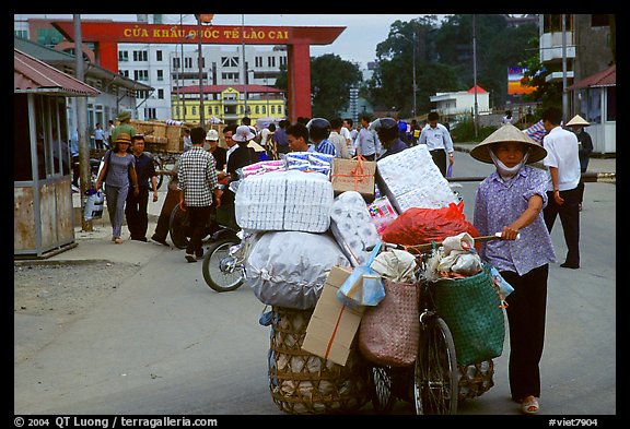 Woman pushing a bicycle loaded with cheap goods at the Lao Cai border crossing. Vietnam (color)