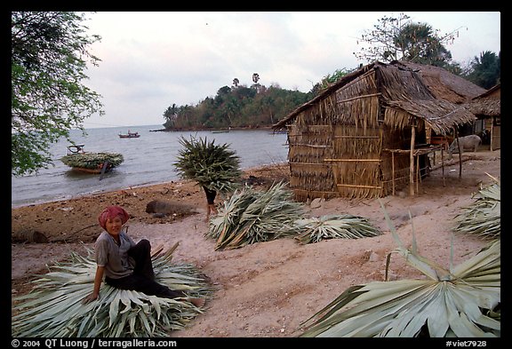 Woman taking a break sitting on leaves used to build a hut. Hong Chong Peninsula, Vietnam (color)