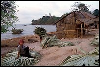 Woman taking a break sitting on leaves used to build a hut. Hong Chong Peninsula, Vietnam