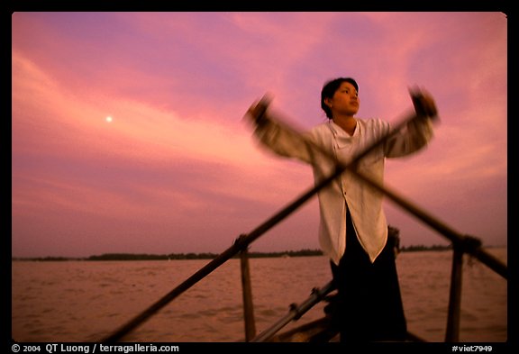 Boater using the X-shaped paddle characteristic of the Delta, sunset. Can Tho, Vietnam