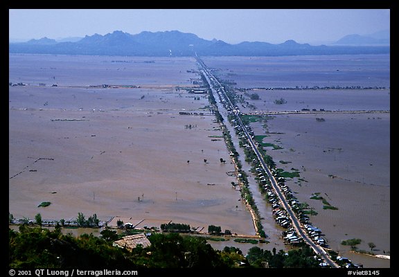 Stilts houses line a road traversing inundated rice fields, seen from Sam mountain. Cambodia is in the far. Chau Doc, Vietnam