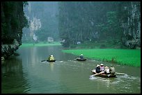 Villagers go to work floating a shallow river in Tam Coc. Ninh Binh,  Vietnam