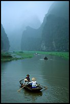 Villagers going by boat to their fields, amongst misty cliffs, Tam Coc. Ninh Binh,  Vietnam (color)